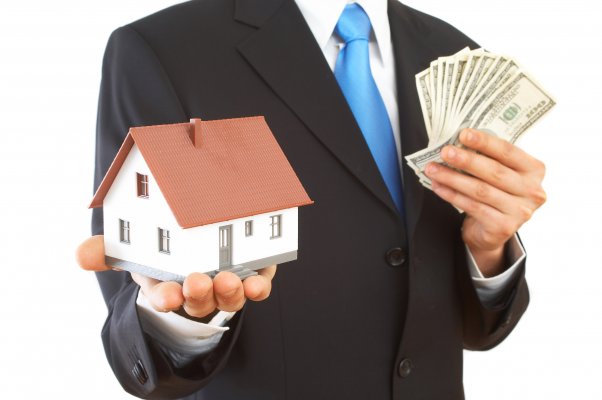 man in suit holding money and miniature house debt consolidation